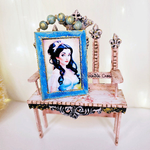 Small decorative chair with a framed picture of a princess on a white background