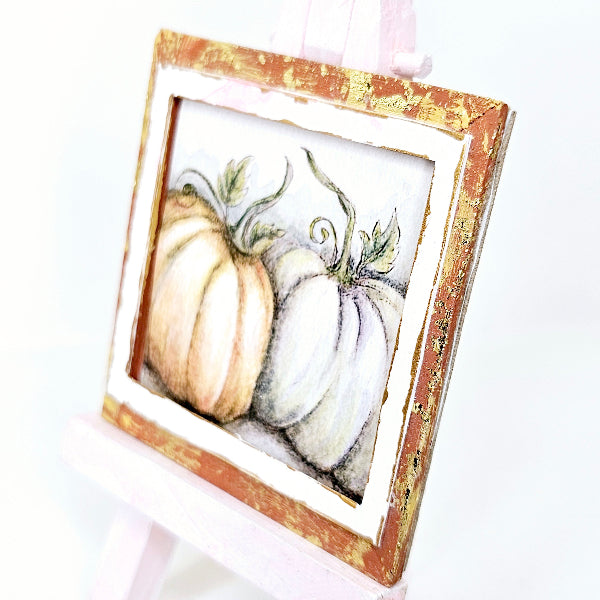 Framed artwork of pumpkins with a gold frame on a white background
